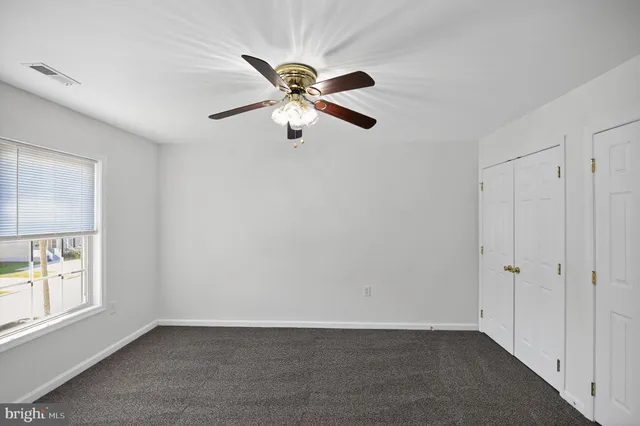 an empty room with windows and fan