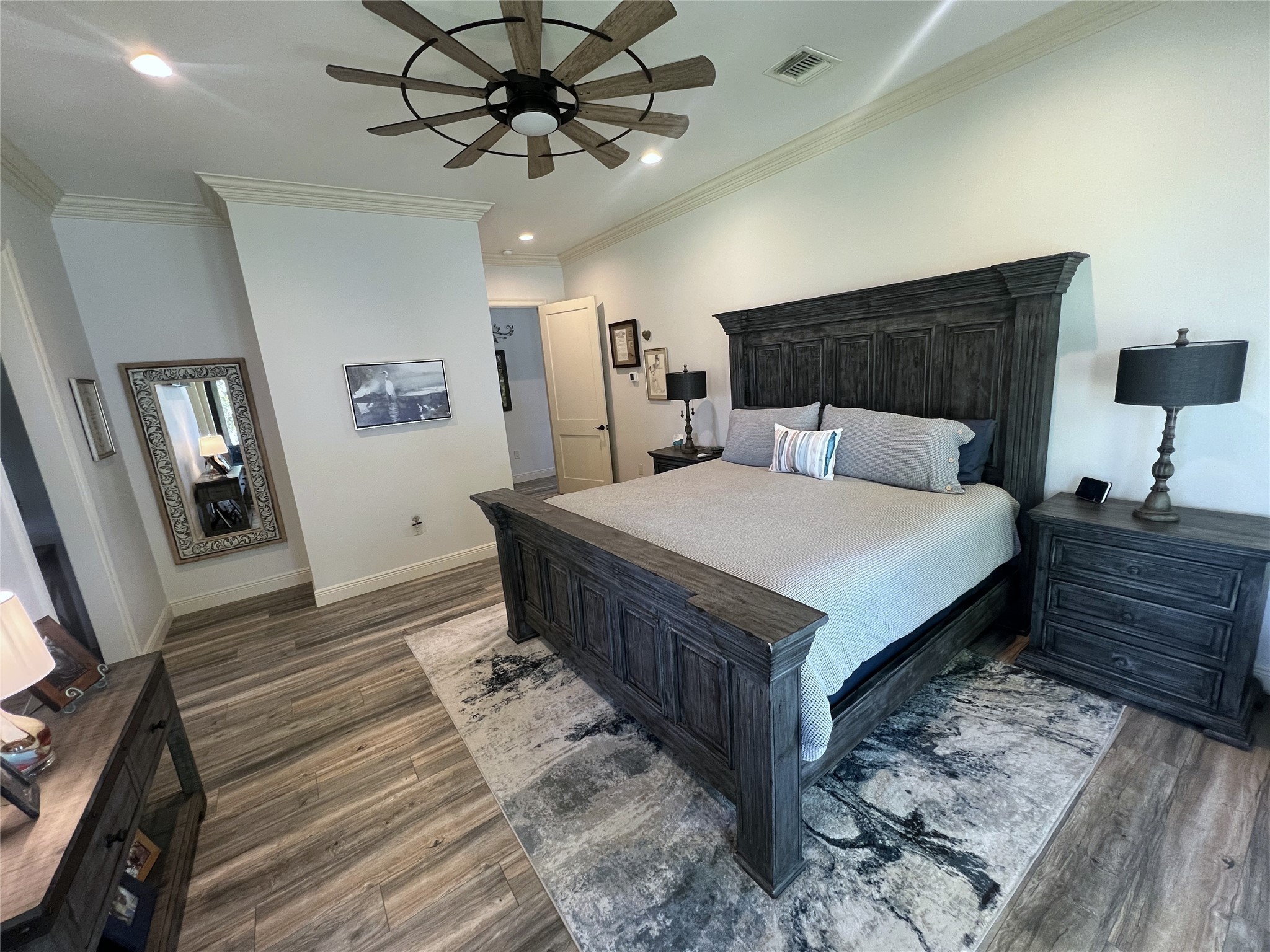 7165 Backridge Road Sabine Pass, TX 77655 - Photo 13 of 49 a large bedroom with a bed a dresser and wooden floor