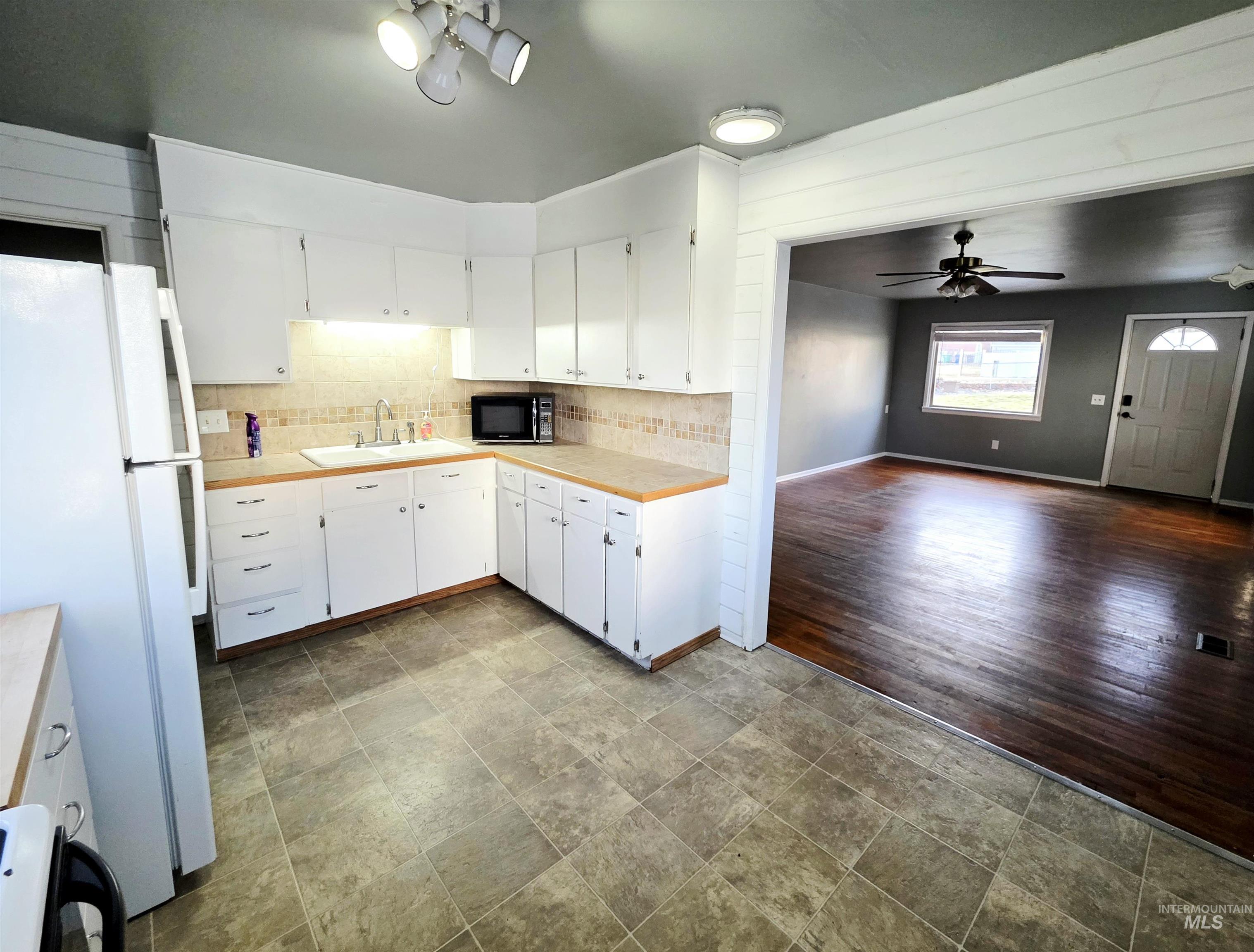 2127 12th Avenue Lewiston, ID 83501 - Photo 7 of 27 Kitchen with white cabinetry, freestanding refrigerator, stone finish flooring, ceiling fan, and decorative backsplash