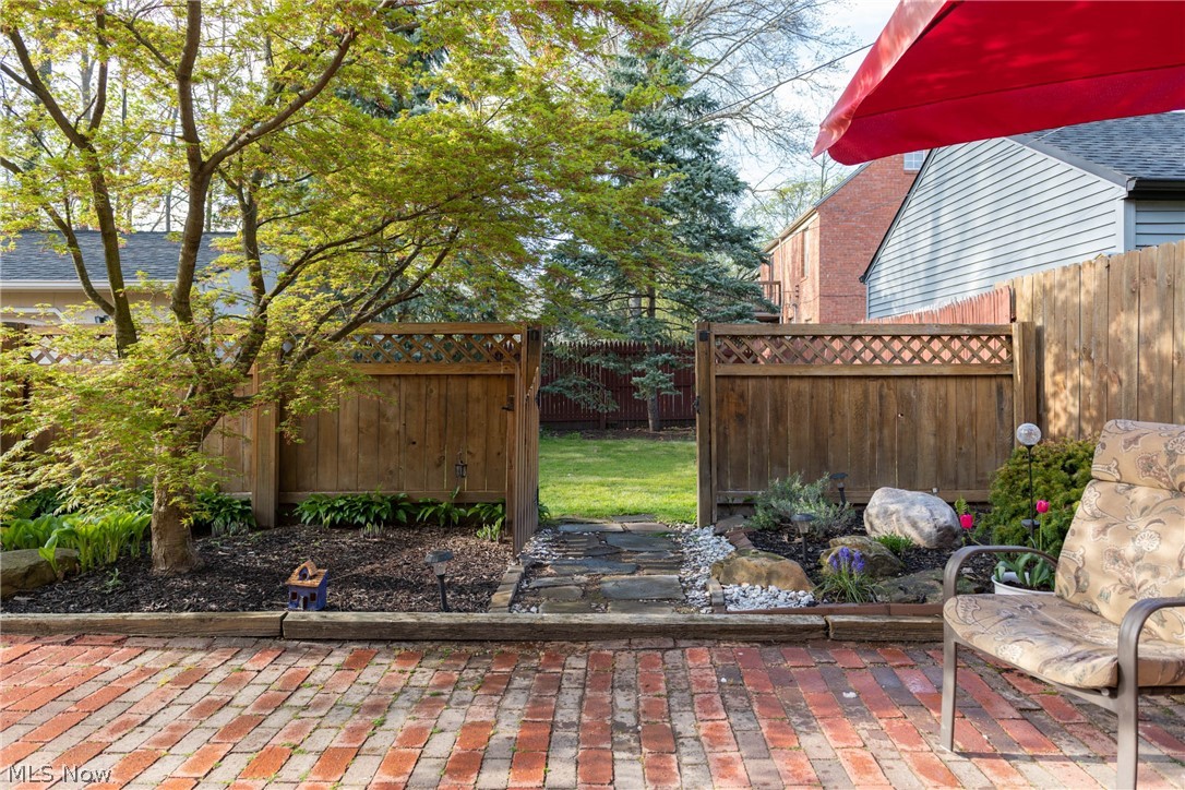 3433 Bradford Road Cleveland, OH 44118 - Photo 10 of 35 Viewed from the back dr, off the Din rm, is this serene courtyard & grass area ahead, that can be closed off w/ the gate. It's accented by pretty foliage, lg decorative rocks & a brick surface. Fencing around the courtyard was treated in 2017/18.