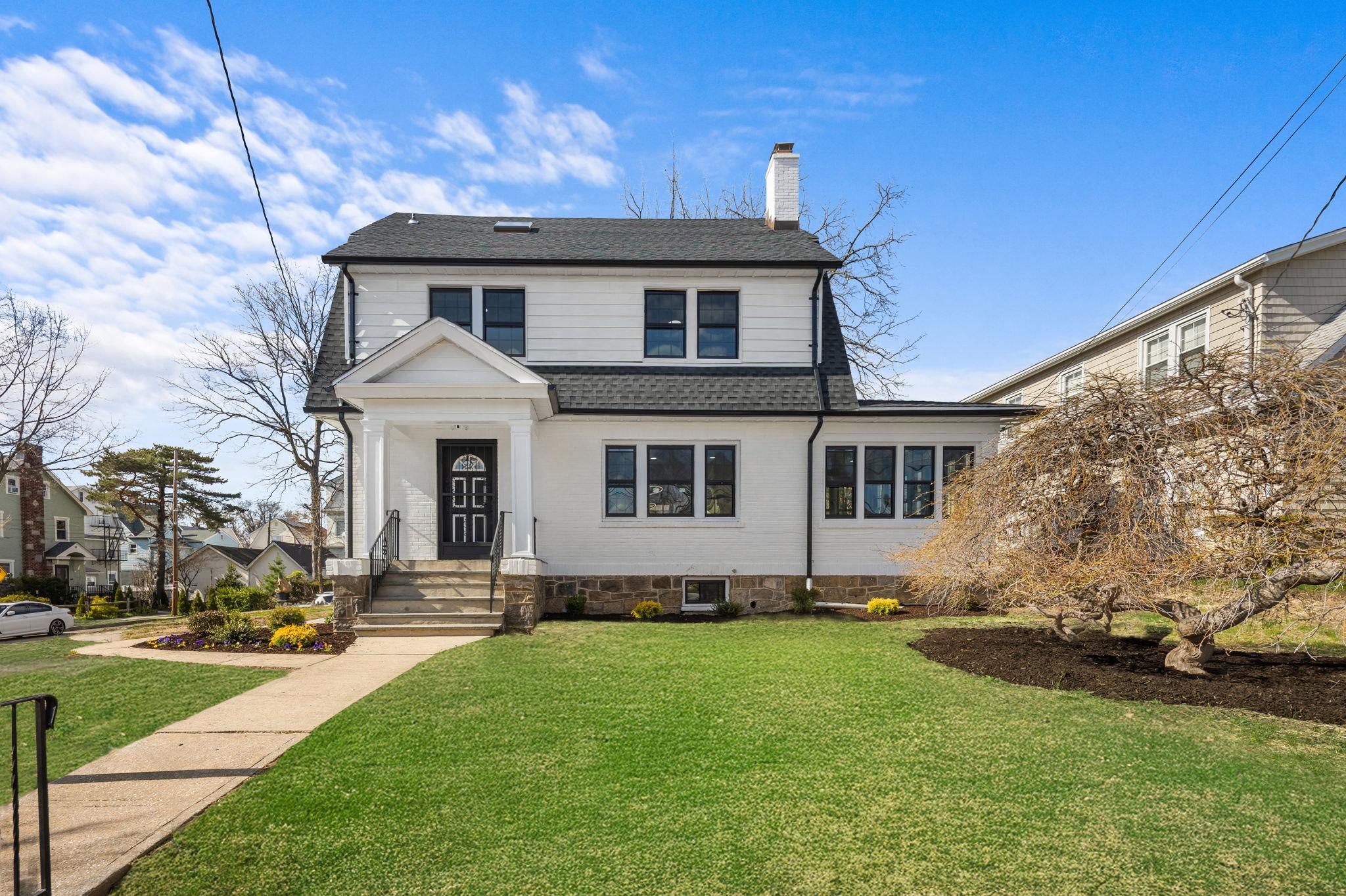 View of front of home featuring a front yard, a chimney, and a shingled roof