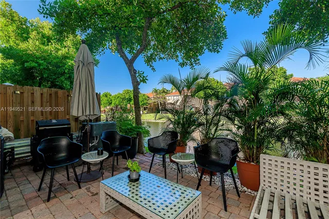 a backyard with table and chairs potted plants and a large tree