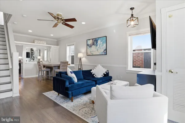 a living room with couches and kitchen view with wooden floor