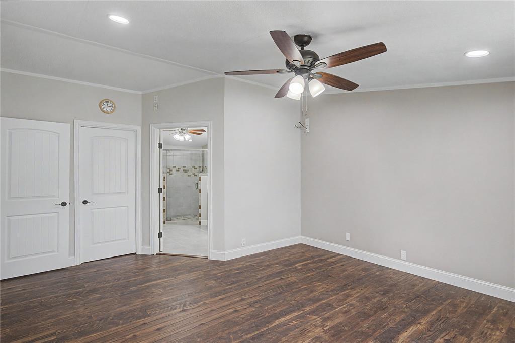 1701 Central Road Weatherford, TX 76088 - Photo 23 of 40 Primary bedroom with ornamental molding, dark wood-style flooring, ceiling fan, recessed lighting, walk in closet, and a view of the ensuite primary bathroom.