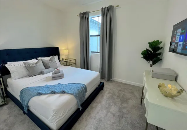a bedroom with a bed and a potted plant on the dresser