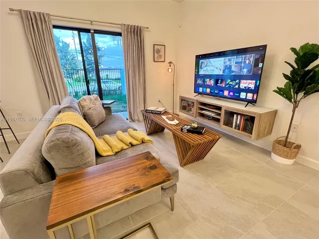 a living room with furniture a flat screen tv and a floor to ceiling window