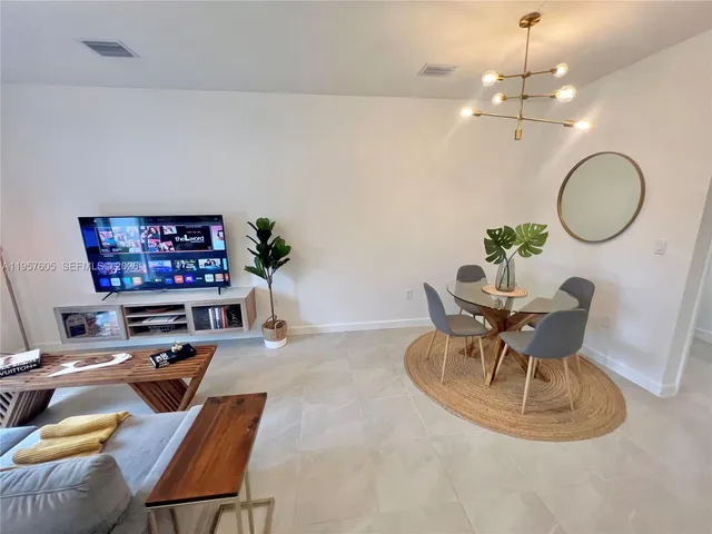 a living room with furniture a dining table and a chandelier