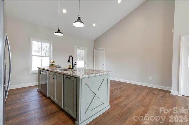 a kitchen with stainless steel appliances granite countertop a sink a stove a refrigerator and island with wooden floor