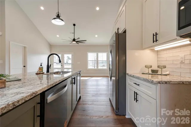 a kitchen with granite countertop a sink stainless steel appliances and cabinets