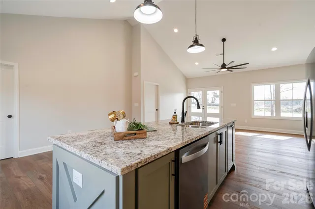 a kitchen with granite countertop a sink cabinets and wooden floor