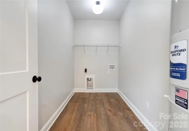 a view of a hallway with wooden floor and a bathroom