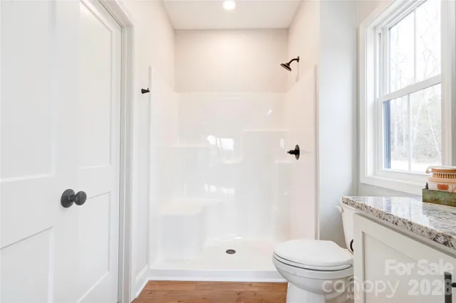 a bathroom with a granite countertop sink a toilet and shower