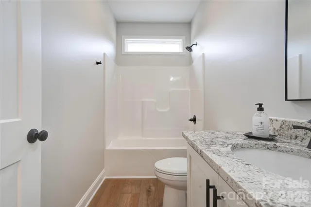 a bathroom with a granite countertop sink a toilet and shower