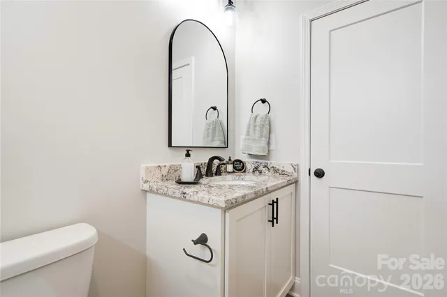 a bathroom with a granite countertop sink a toilet and a mirror
