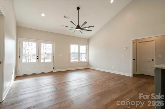 a view of an empty room with window and wooden floor