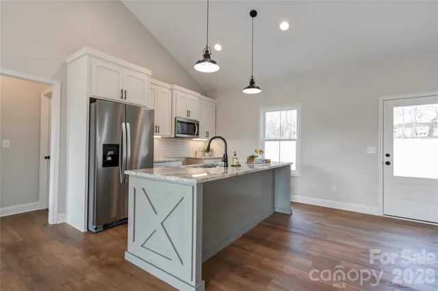 a kitchen with stainless steel appliances granite countertop a refrigerator a sink dishwasher a stove and a refrigerator with wooden floor