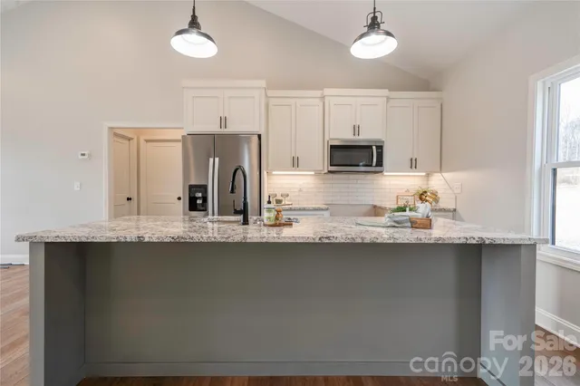 a kitchen with stainless steel appliances granite countertop a sink a stove a refrigerator a center island and cabinets