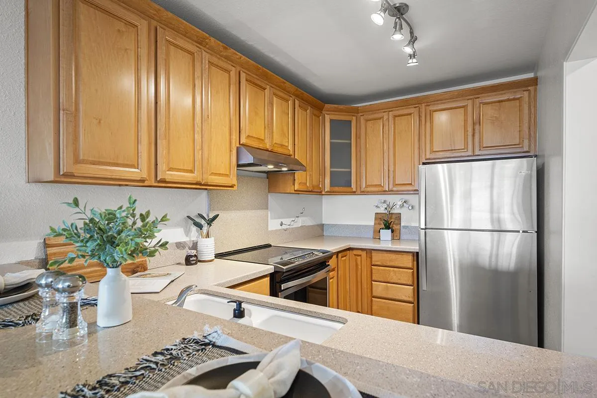 3570 1st Avenue, Unit 1 San Diego, CA 92103 - Photo 21 of 55 a kitchen with stainless steel appliances granite countertop a refrigerator a sink dishwasher and white cabinets with wooden floor