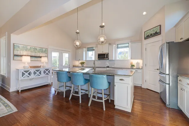 a kitchen with stainless steel appliances a dining table chairs refrigerator sink and cabinets