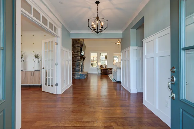 a view of a hallway with wooden floor and a chandelier