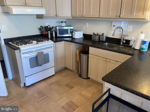 a kitchen with granite countertop a stove sink and cabinets