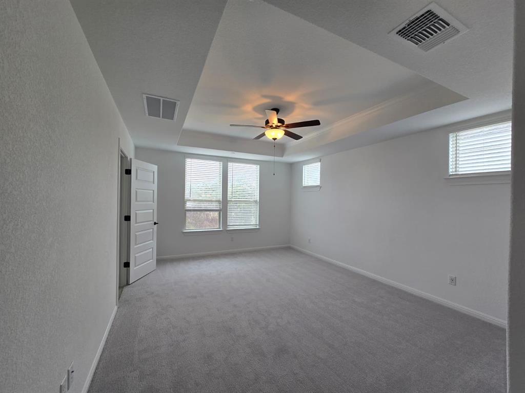 2725 Woodall Drive, Unit 204 Cedar Park, TX 78613 - Photo 7 of 14 Empty room featuring a tray ceiling, carpet floors, and a ceiling fan