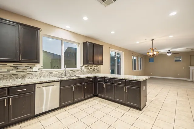 a large kitchen with granite countertop a sink and white cabinets