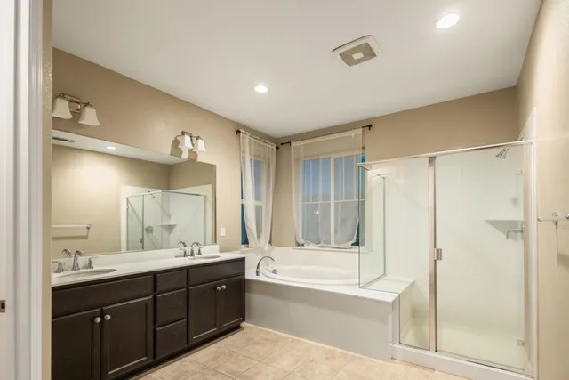a bathroom with a tub sink shower and mirror
