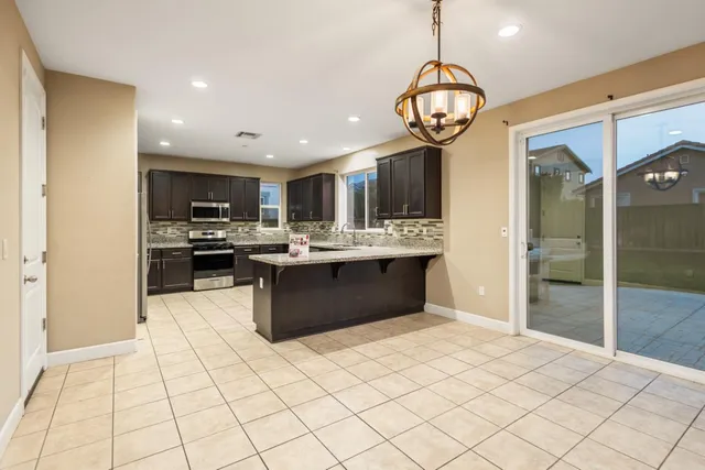 a kitchen with kitchen island granite countertop a sink a counter top space cabinets and stainless steel appliances