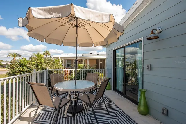 a patio with wooden floor a yard a table and chairs