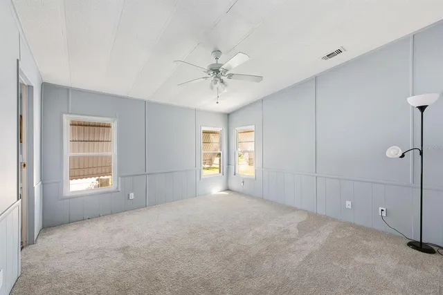 an empty room with windows and ceiling fan