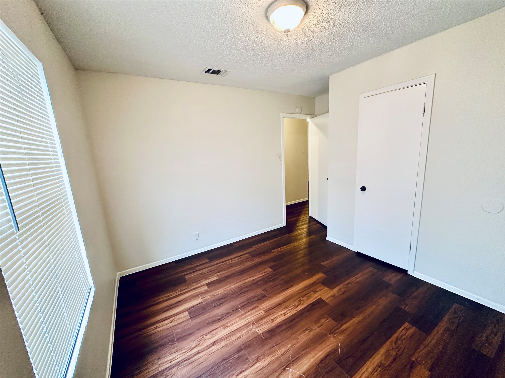 12505 Turtle Rock Road, Unit A Austin, TX 78729 - Photo 28 of 38 Rich hardwood-style flooring extends through this versatile room, illuminated by natural light from a generous window.