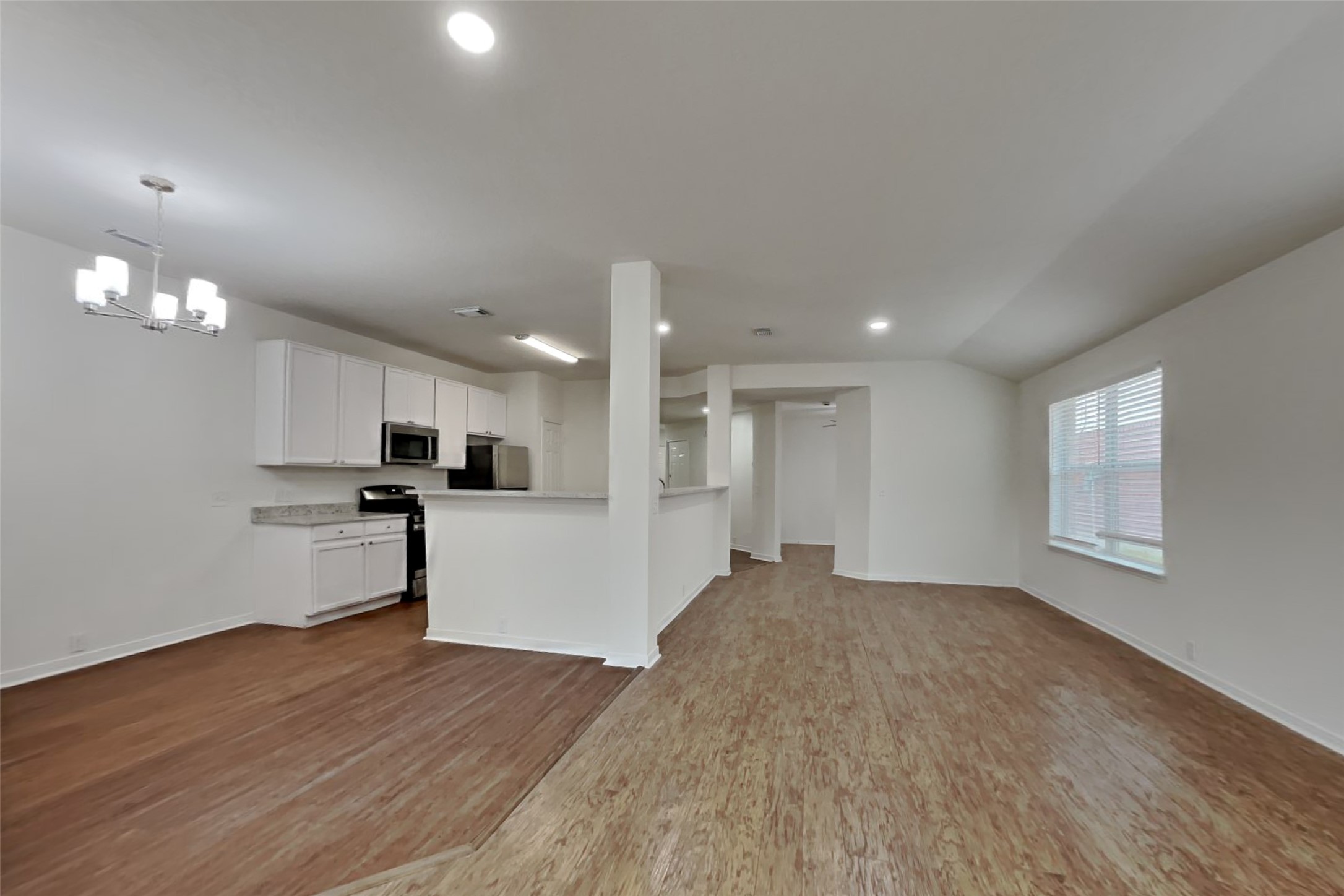 10414 Falling River Drive Houston, TX 77095 - Photo 4 of 18 a view of an empty room and kitchen with wooden floor