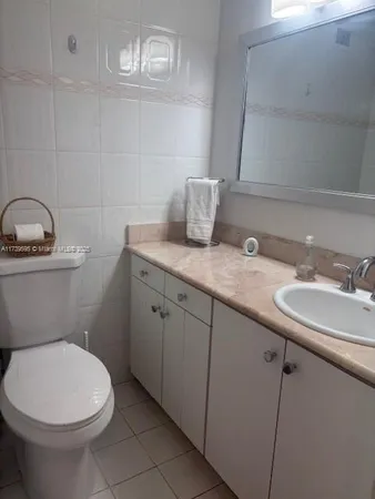 a bathroom with a granite countertop toilet sink and mirror