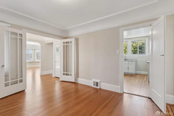 an empty room with wooden floor and windows