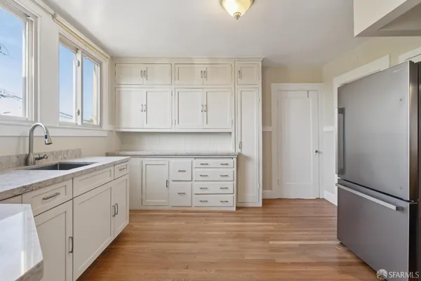 a kitchen with white cabinets and refrigerator