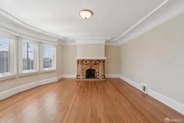 wooden floor fireplace and windows in an empty room