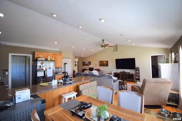 a kitchen with stainless steel appliances granite countertop a stove top oven a sink a dining table and chairs with wooden floor