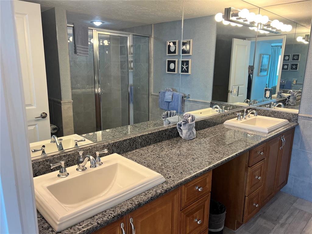 1001 Point Of Rocks Road, Unit 611 Sarasota, FL 34242 - Photo 18 of 39 a bathroom with a granite countertop sink a large mirror and a shower