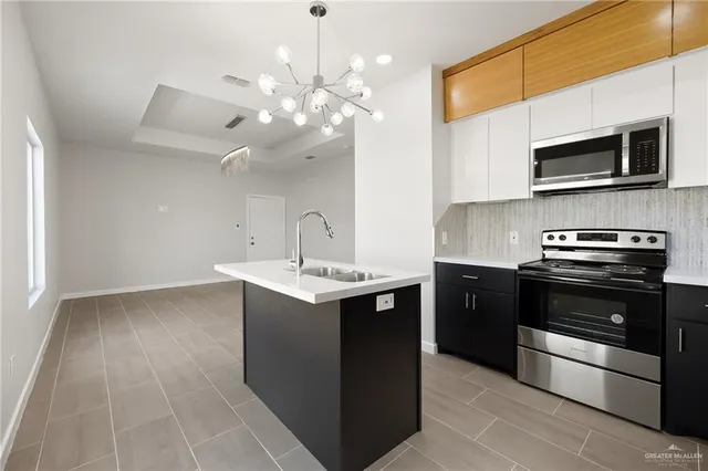 a kitchen with stainless steel appliances a sink dishwasher a stove top oven a refrigerator with island and cabinets