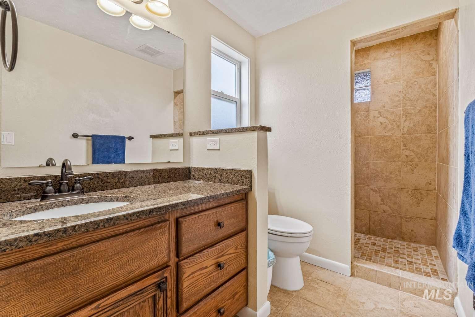 8720 Cornwall Drive Boise, ID 83704 - Photo 12 of 24 Bathroom featuring vanity, a tile shower, and light tile patterned floors