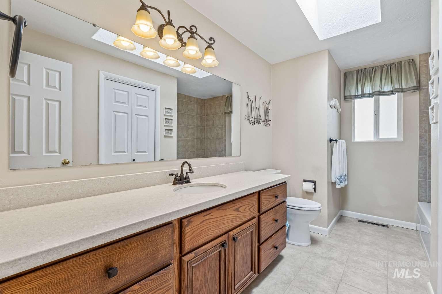 8720 Cornwall Drive Boise, ID 83704 - Photo 14 of 24 Full bathroom featuring a skylight, vanity, light tile patterned floors, and shower / bathtub combination