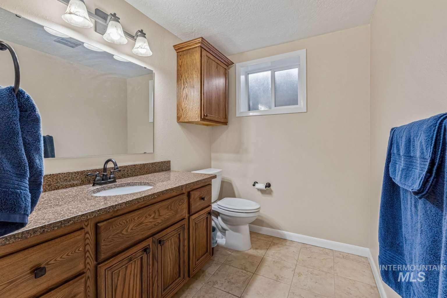 8720 Cornwall Drive Boise, ID 83704 - Photo 17 of 24 Bathroom with a textured ceiling, vanity, and light tile patterned floors