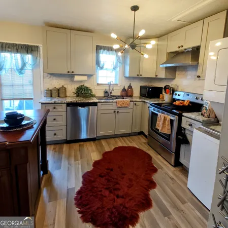 a kitchen with granite countertop a stove a sink dishwasher and a refrigerator
