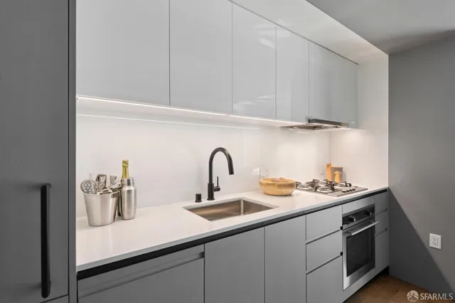 a kitchen with a sink and a stove with wooden floor