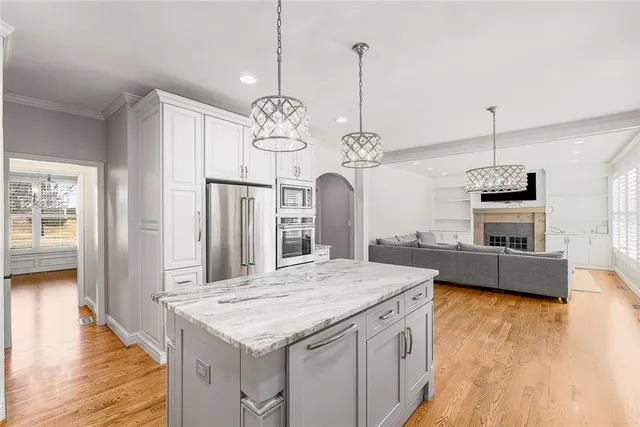 a kitchen with stainless steel appliances kitchen island granite countertop a stove top oven a refrigerator a sink with island and chairs