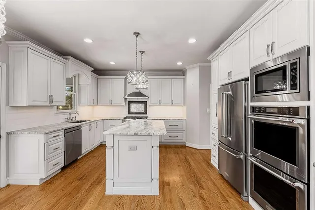 a kitchen with stainless steel appliances kitchen island granite countertop a stove a sink and a refrigerator