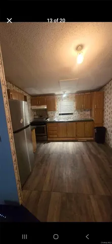 a view of kitchen and empty room with wooden floor