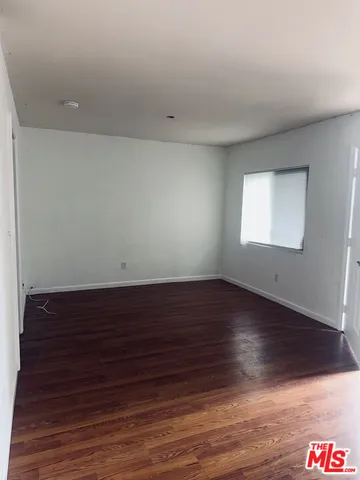 a view of an empty room with wooden floor and closet