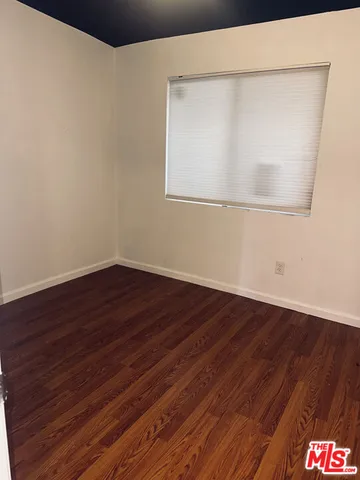 an empty room with wooden floor and window